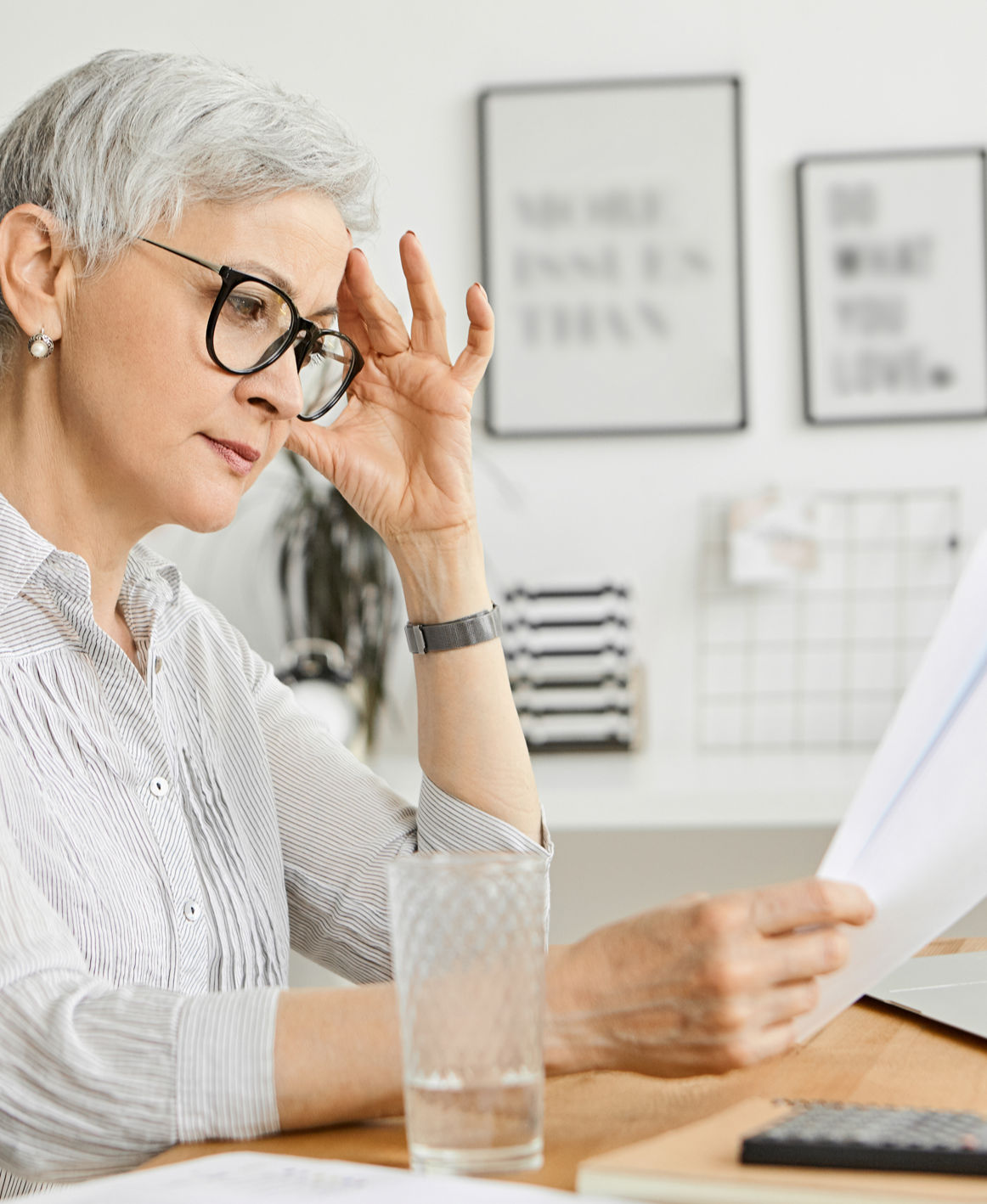 Elderly woman looking at financial documents at a table