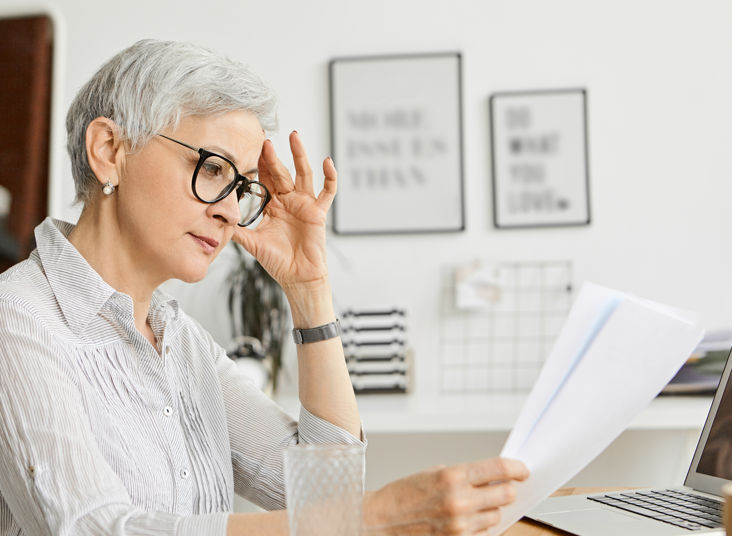 Elderly woman looking at financial documents at a table