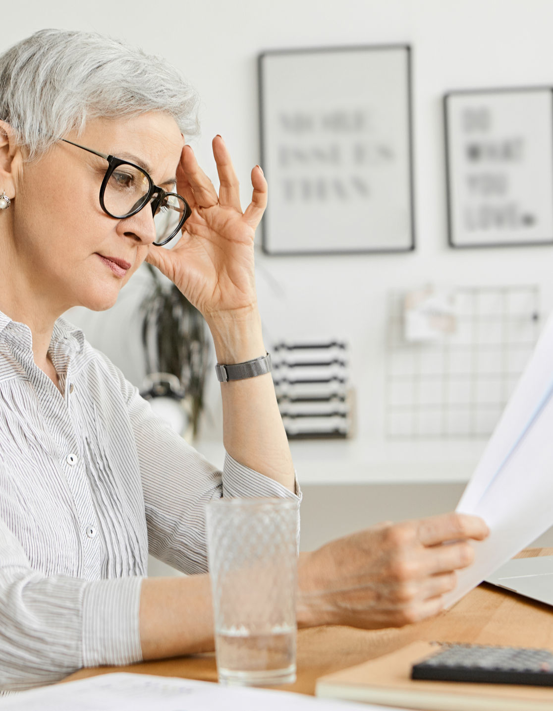 Elderly woman looking at financial documents at a table