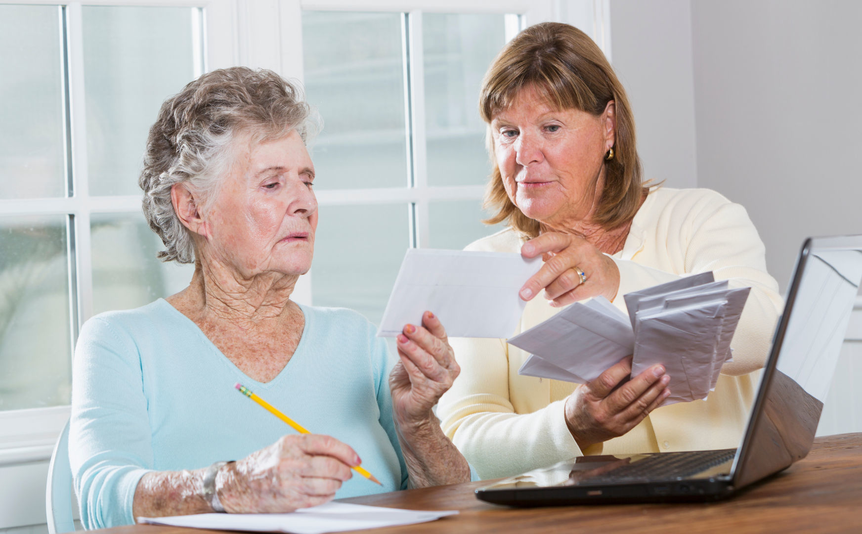 An elderly woman and her daughter looking at bills