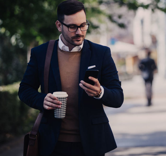 A business professional walking down the street looking at his phone